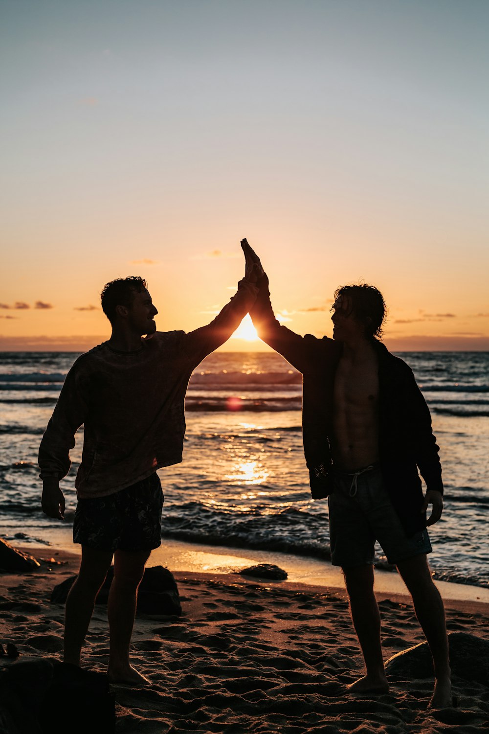 dois homens batendo palmas um para o outro na praia