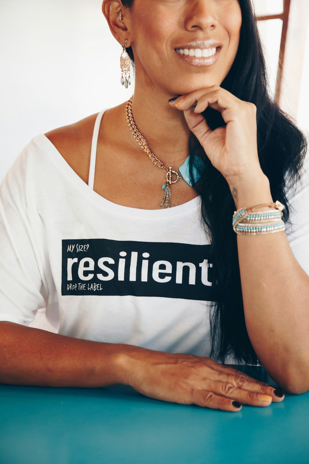 woman smiles while sitting next to cyan wooden tabletop