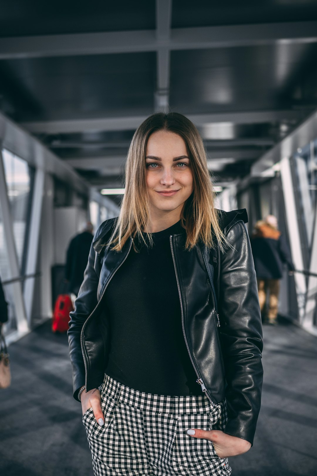 woman standing on catwalk bridge wearing black leather jacket