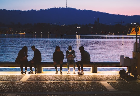 five people sitting near body of water in Zurich Switzerland