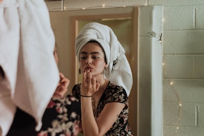 woman putting makeup in front of mirror