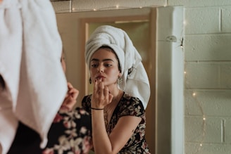 woman putting makeup in front of mirror