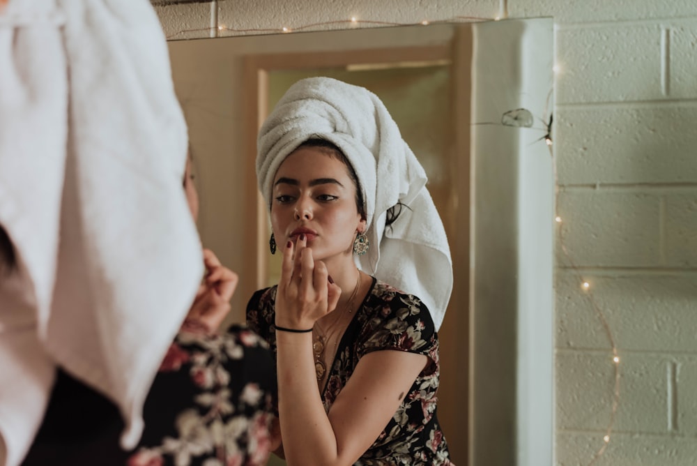 mulher colocando maquiagem na frente do espelho
