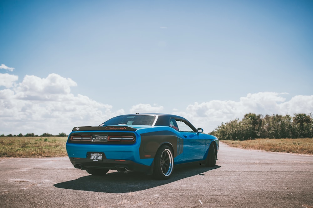 blue sports car parked on the middle of road