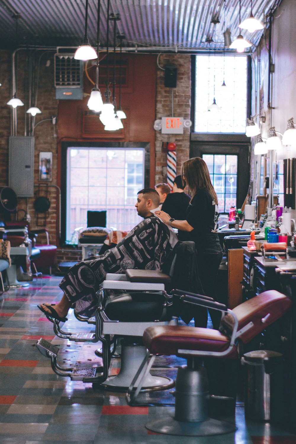 Homme debout à côté d’un homme assis sur une chaise de barbier
