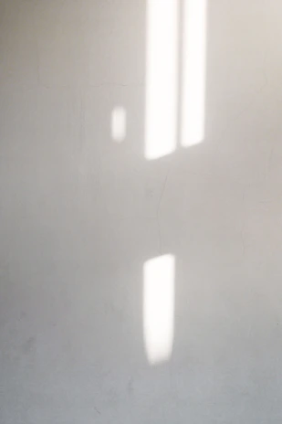 An abstract play of light and shadow on a white wall, creating a peaceful atmosphere.