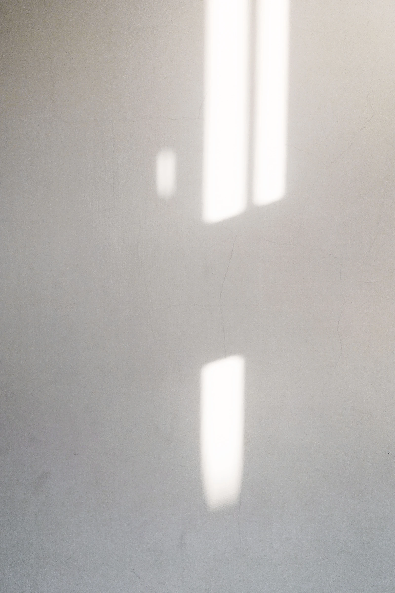 Soft rectangles of window light falling across a plain wall.