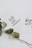 Two white cards with inspirational quotes written in black cursive text are overlapping. One card reads 'faith can move mountains' and the other says 'be your brave'. A dried branch with green leaves is placed beneath the cards, adding a natural touch.