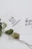 Two white cards with inspirational quotes written in black cursive text are overlapping. One card reads 'faith can move mountains' and the other says 'be your brave'. A dried branch with green leaves is placed beneath the cards, adding a natural touch.