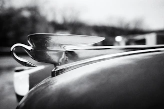 Sleek close-up of golden vintage car hood ornament gleaming under soft ambient lighting.