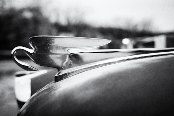 Sleek close-up of golden vintage car hood ornament gleaming under soft ambient lighting.
