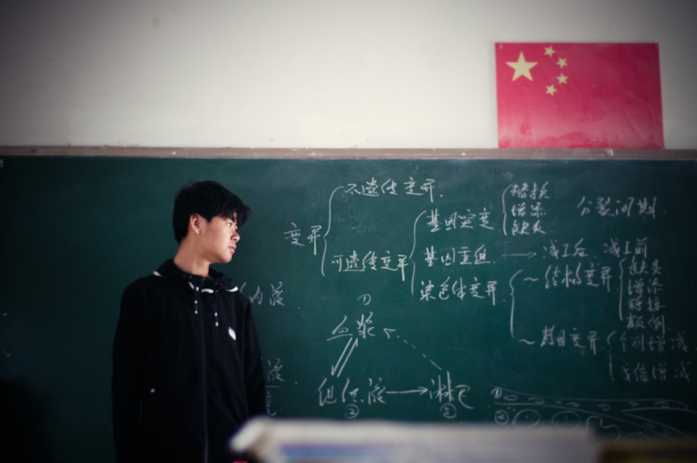 man standing in front of chalkboard inside classroom