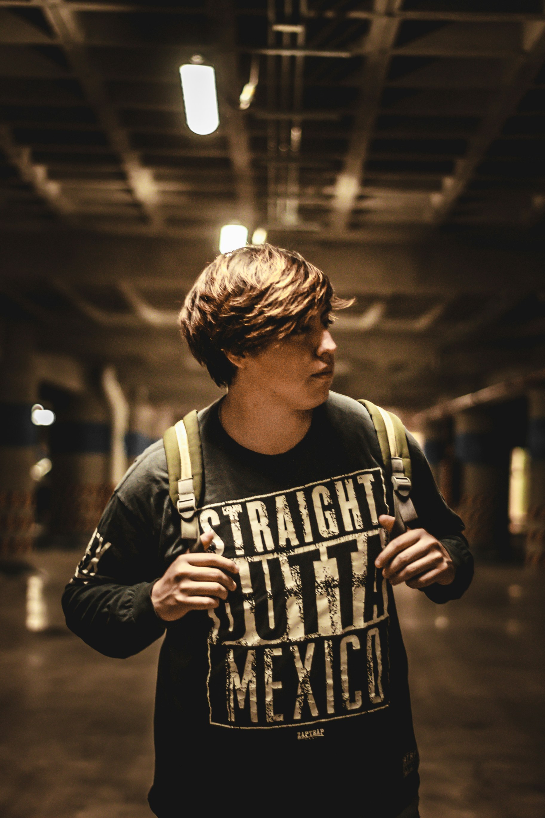 Teenager looking offscreen with unreadable expression, dramatic side light, urban background