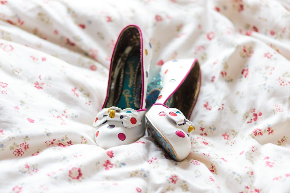 pair of white-and-multicolored sandals on white and red floral textile