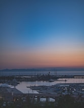A calm harbor scene at dawn with ships docked and soft blue tones reflecting the maritime theme.