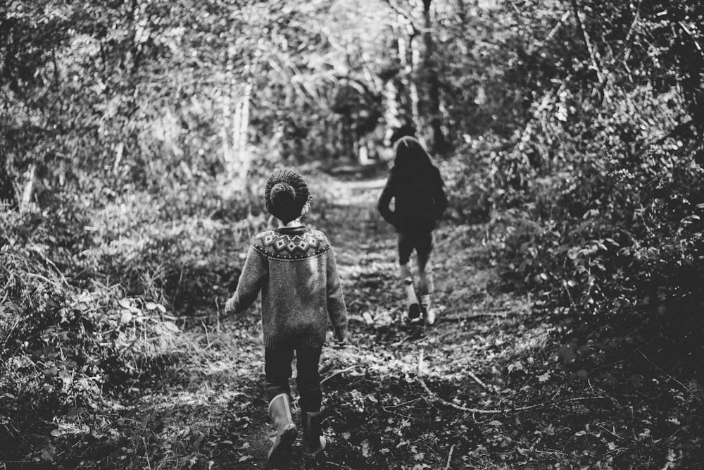 foto em escala de cinza de duas crianças cercadas por plantas