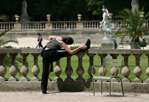 Sunlit outdoor shot of a person stretching before a workout, with vibrant cityscape of Cali in the background