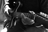 An artistic shot of a musician playing guitar, focused on hands and instrument details.