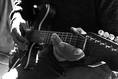 An artistic shot of a musician playing guitar, focused on hands and instrument details.