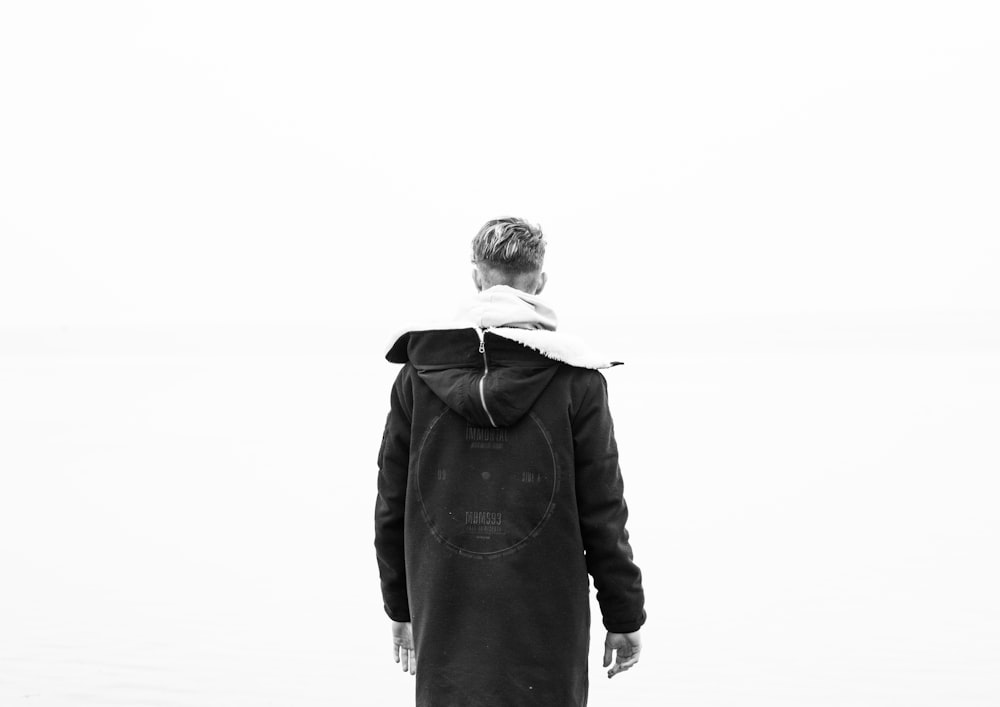 man standing wearing black overcoat hoodie