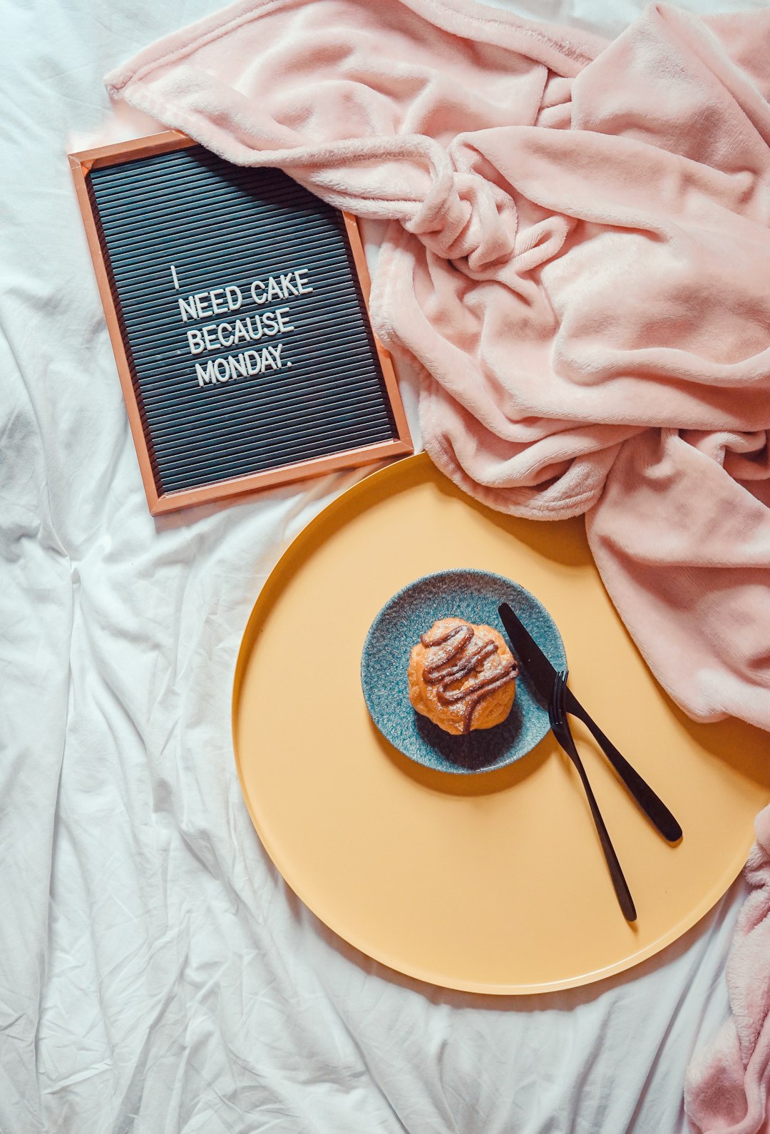 muffin beside knife and fork on saucer beside blanket