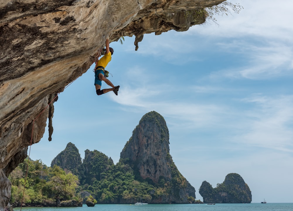 uomo che si arrampica sulla scogliera accanto alla spiaggia