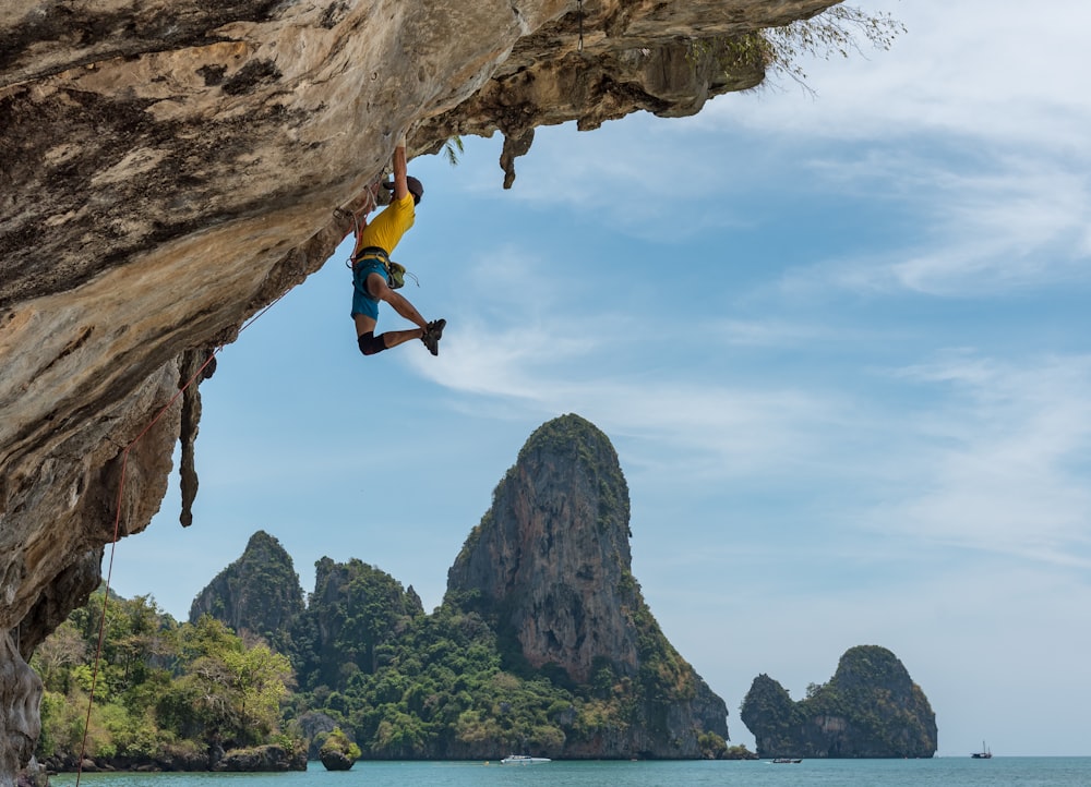 man climbing cliff beside beach