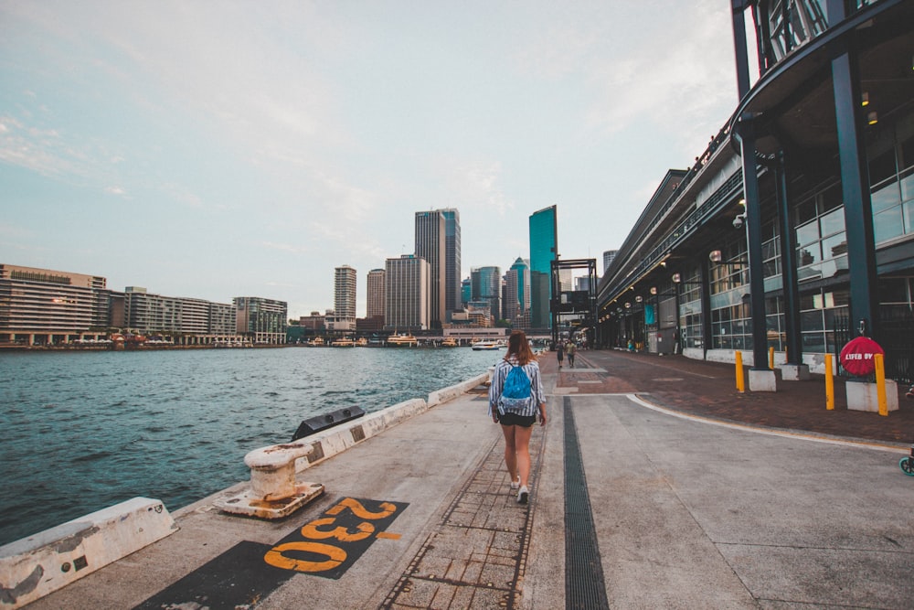 man in blue t-shirt and blue denim shorts walking on sidewalk during daytime