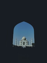 The majestic Taj Mahal glowing softly under a clear blue sky.