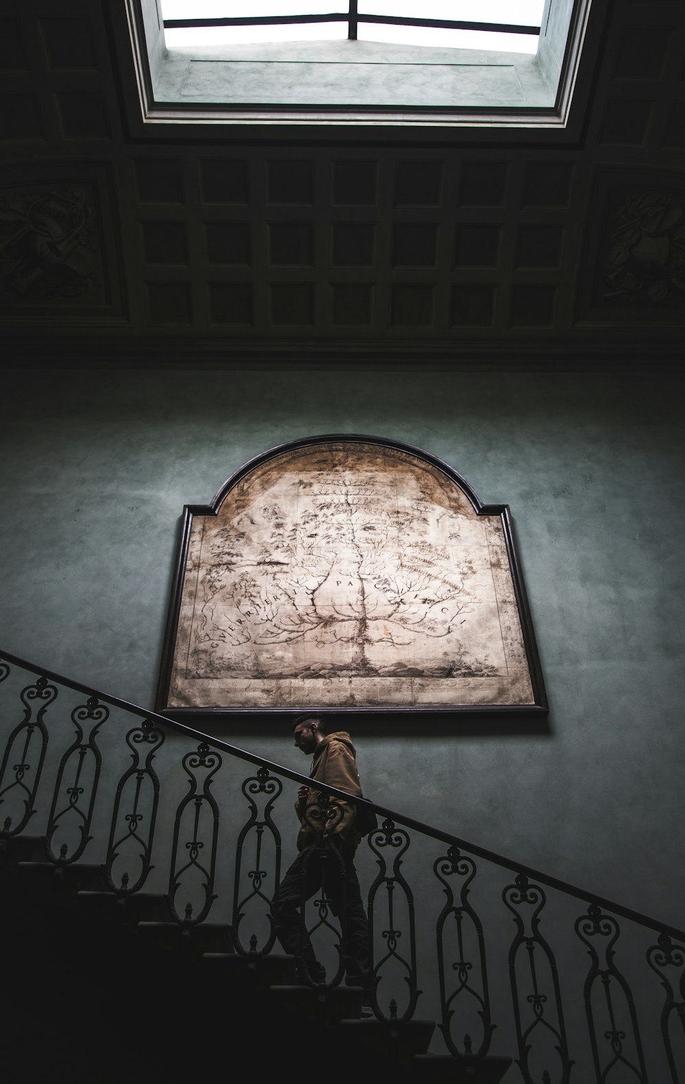 man walking on stairs beside painting under open ceiling building