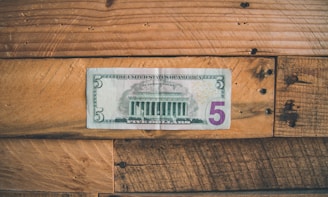 5 U.S dollar on brown wooden surface