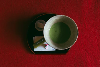 Close-up of fine wasanbon sugar crystals resting on a traditional Japanese ceramic plate beside a bamboo whisk.