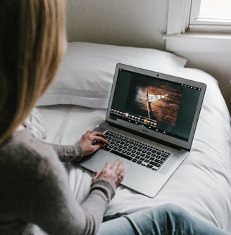 woman using gray laptop on bed