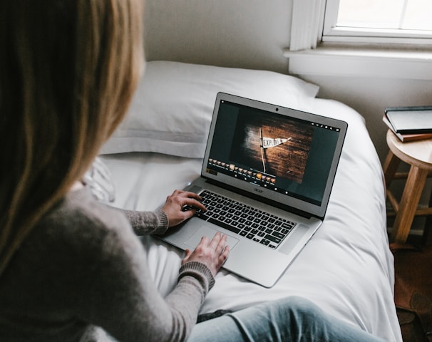 woman using gray laptop on bed