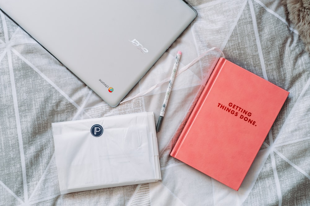 Getting Things Done book beside gray Acer Chromebook on gray textile