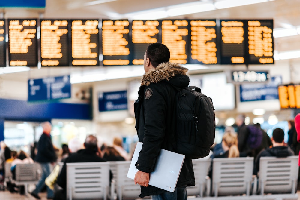 hombre de pie dentro del aeropuerto mirando el tablón de anuncios del horario de vuelo LED