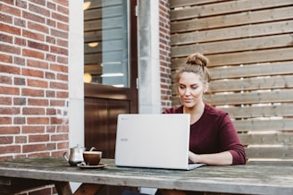 woman sitting and holding white Acer laptop near brown wooden wall