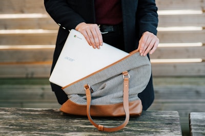 Close-up of hands handing over a laptop to a licensed recycling partner.