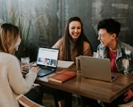 three people sitting in front of table laughing together