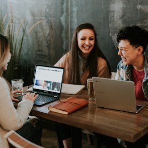 three people sitting in front of table laughing together