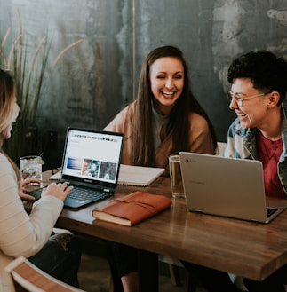 three people sitting in front of table laughing together