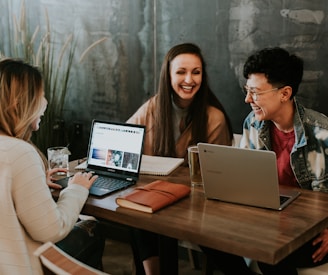 three people sitting in front of table laughing together