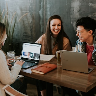 three people sitting in front of table laughing together