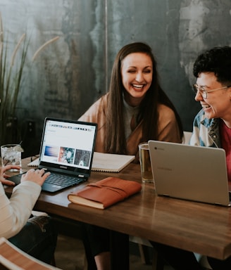 three people sitting in front of table laughing together