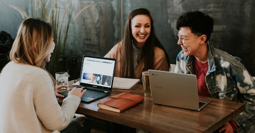 three people sitting in front of table laughing together