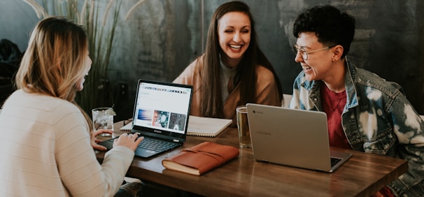 three people sitting in front of table laughing together