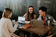 three people sitting in front of table laughing together