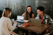 three people sitting in front of table laughing together