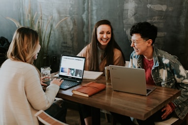 three people sitting in front of table laughing together