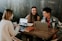 three people sitting in front of table laughing together